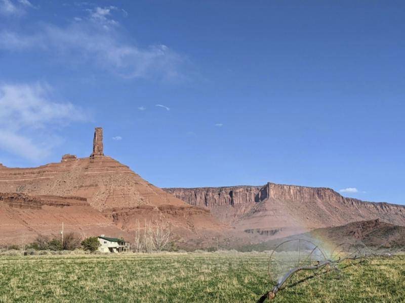 Castleton Tower rising above green fields in Castle Valley, near Moab