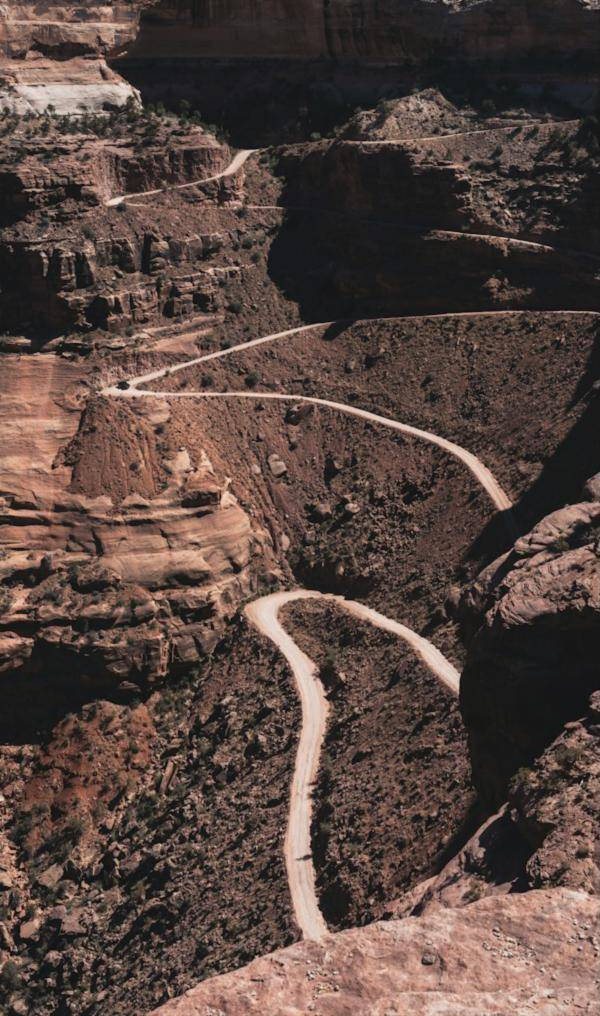A dirt road switching back down the wall of a deep red rock canyon